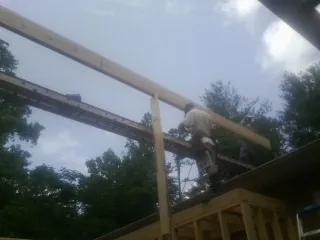 Carpenter setting a ridge beam over a new addition frame — Ice Dam Removal by Roofing Brothers in Ireton