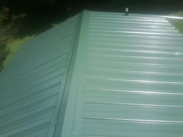 New green metal panels meeting at the ridge of a roof — Flat Roof Repair work by our crew in Ireton