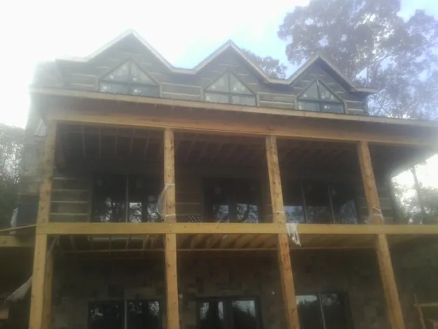 Dormers and porch framing on a large log home under construction — Roof Coating work by our crew in Ireton