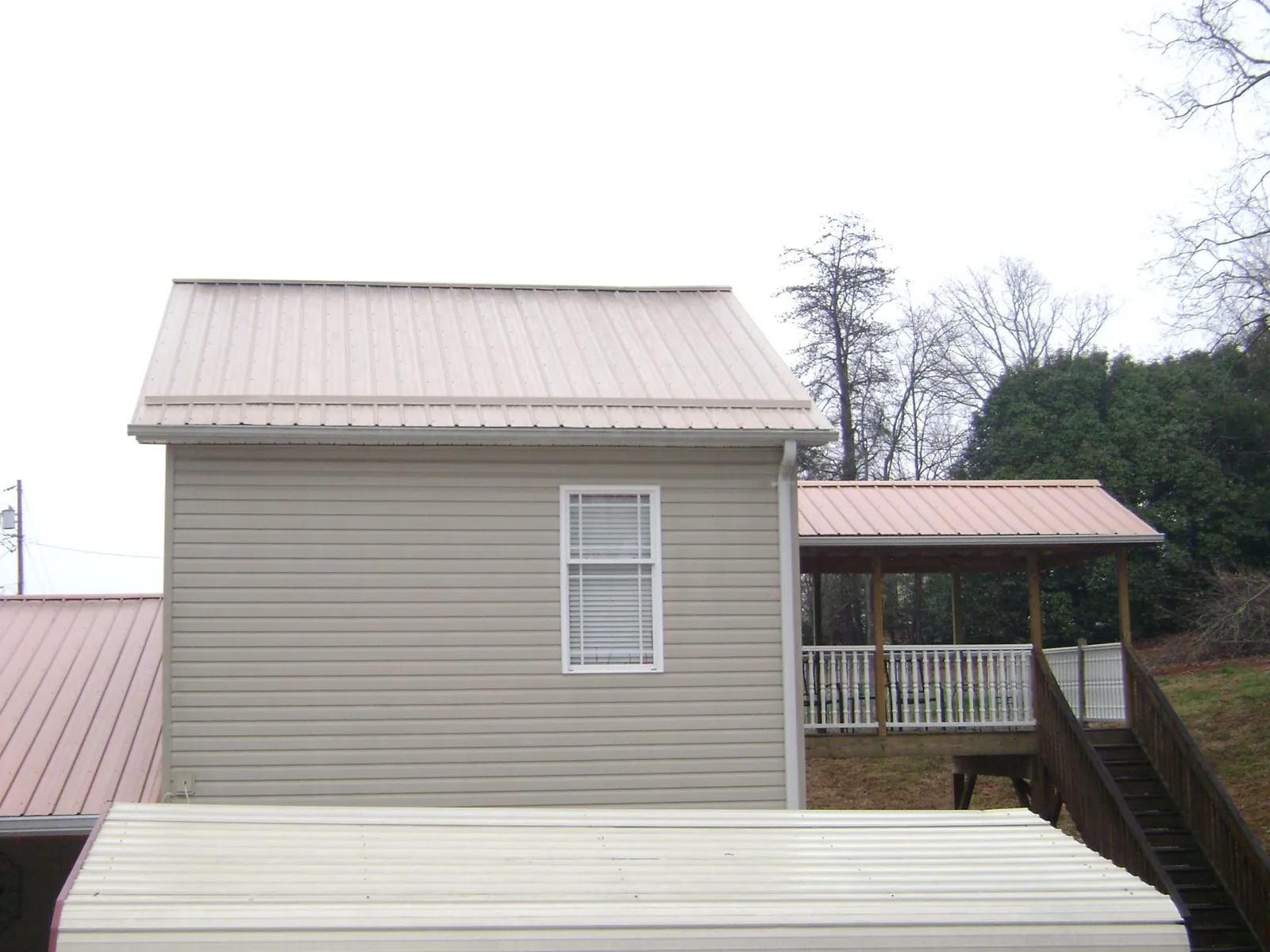 Tan metal roofs on a two story addition and attached porch, from a Roof Replacement job in Ireton