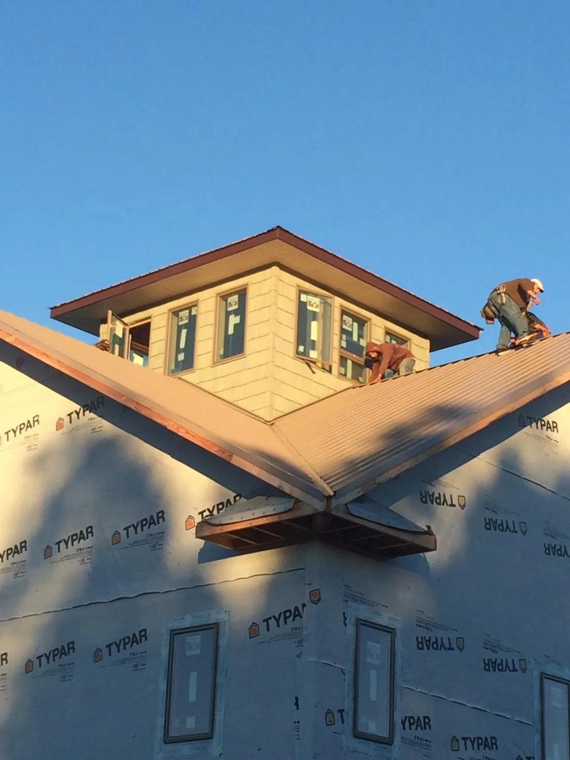 Roofers working around a rooftop cupola on a new metal roof at sunset — Roof Waterproofing in Ireton by Roofing Brothers
